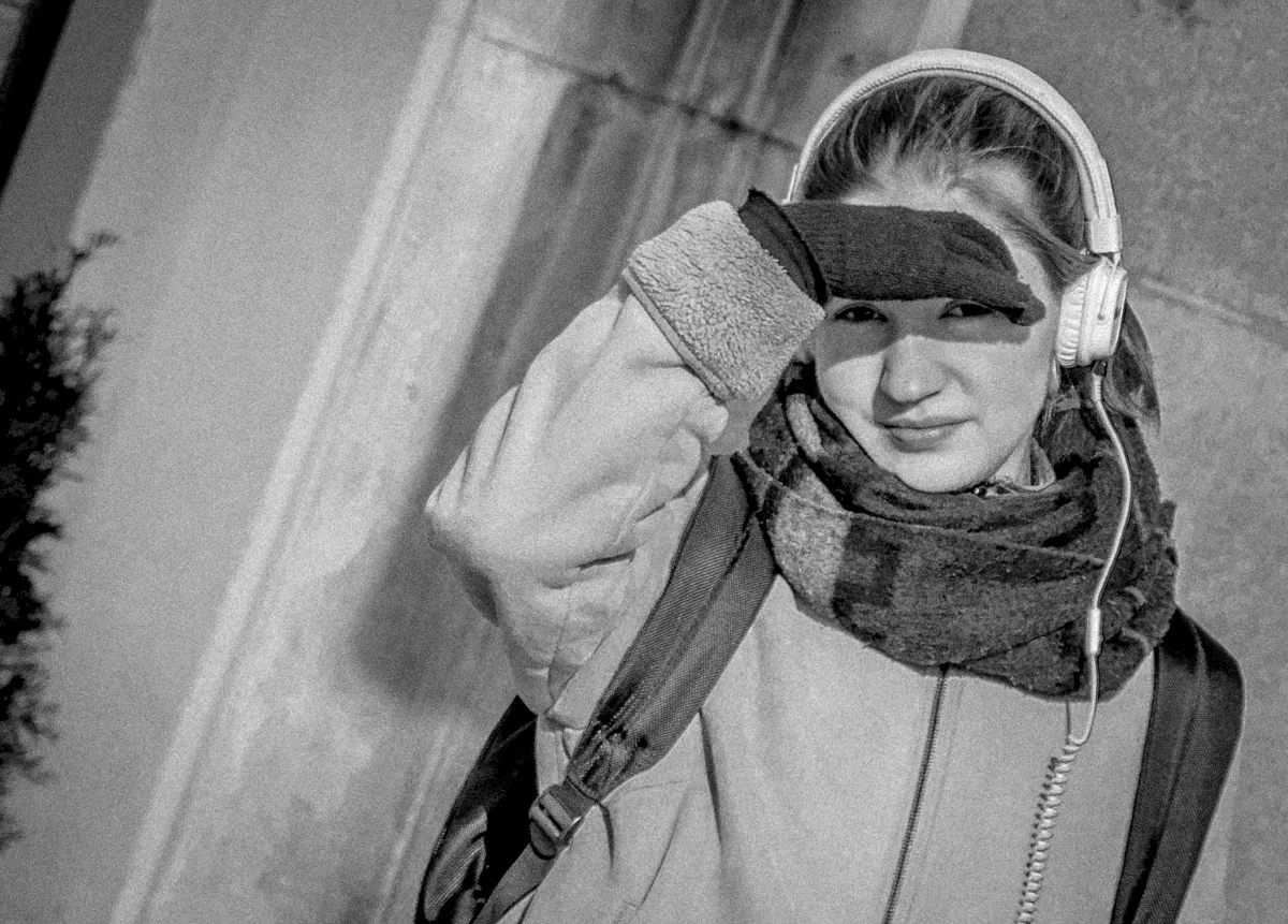 Woman in headphones shading her eyes from low winter sun